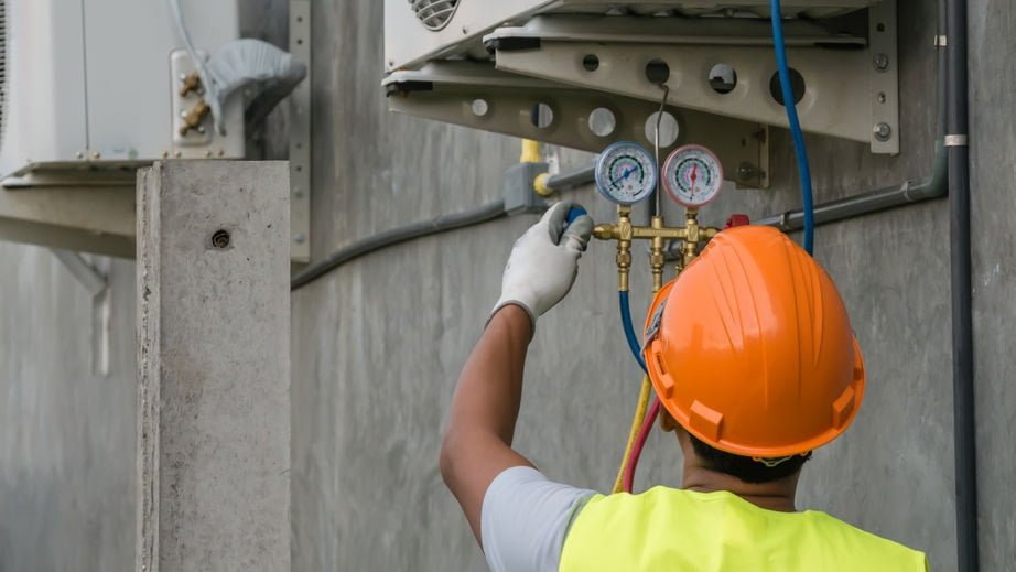 hvac technician checking capacitor on air conditioner