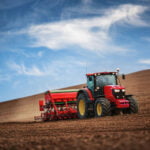 Farmer working on his own in a tractor while seeding crops in a field