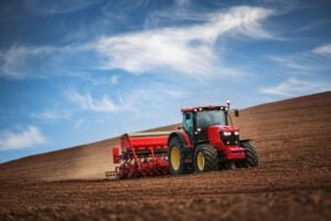 Farmer working on his own in a tractor while seeding crops in a field