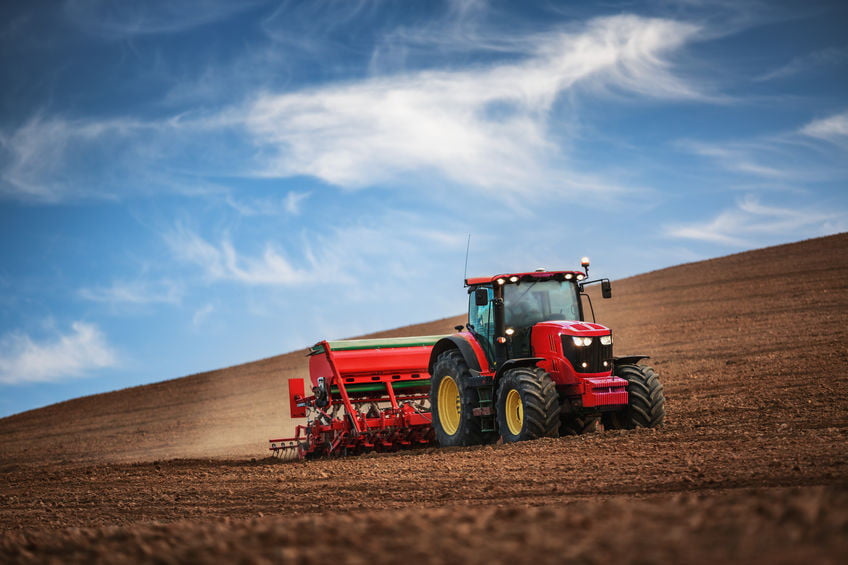 Farmer working on his own in a tractor while seeding crops in a field